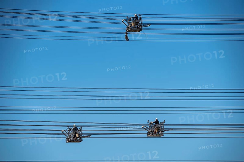 Construction of a new line route, 380 KV extra-high-voltage line between Osterath and Gohr, near Neuss, fitters in line trolleys, on the conductor cables, installing field spacers at great heights, North Rhine-Westphalia, Germany, Europe