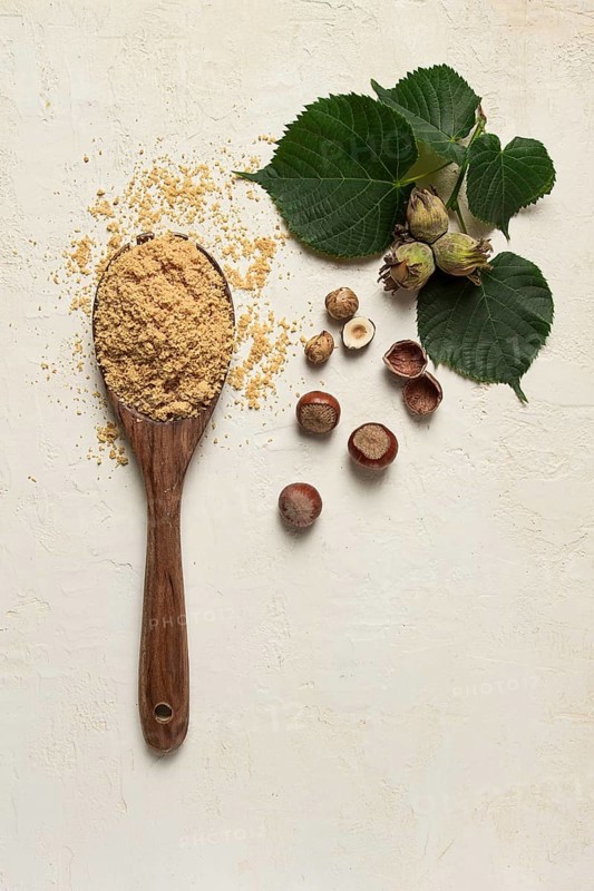 Wooden spoon with hazelnut flour, top view, no people, on a white table