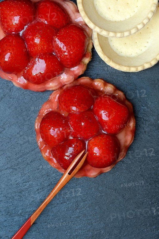 Topped strawberry tartlets with fork and empty tartlet bases