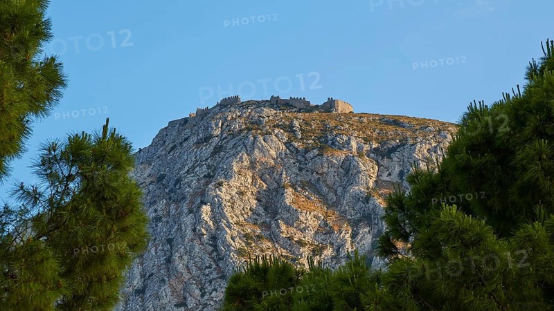 An ancient castle crowning a majestic hilltop, framed by fir trees, Archaic Castle, Akrokorinthos, Corinth, Peloponnese, Greece, Europe