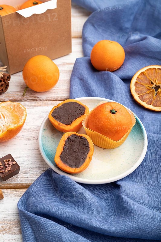 Truffle chocolate tangerine candies on a white wooden background and blue linen textile. Side view, close up