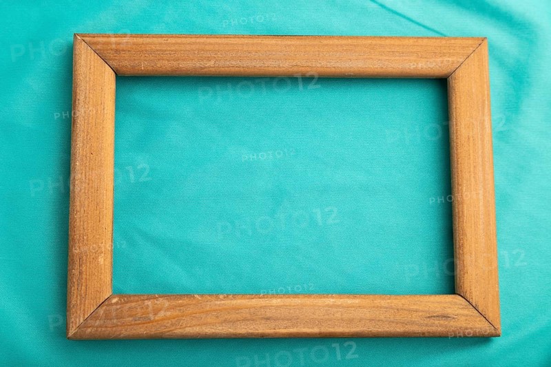 Wooden frame on smooth silk blue tissue. Top view, flat lay, natural textile background and texture