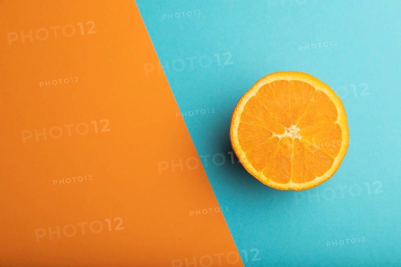 Ripe cut orange on orange and blue pastel background. Top view, flat lay, copy space. Tropical, healthy food, concept, minimalism