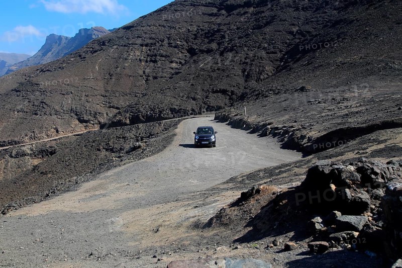 Car driving on unsurfaced road, Atlantic Ocean coast, Jandia peninsula, Fuerteventura, Canary Islands, Spain, Europe