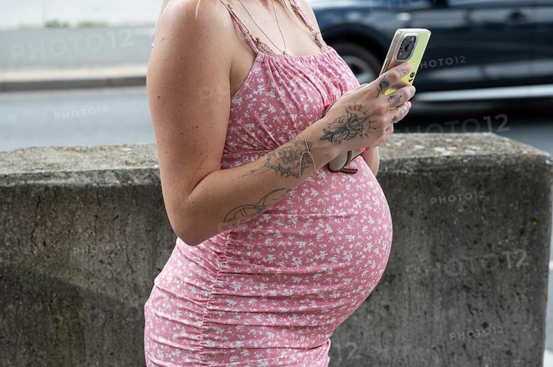Belly of a young pregnant woman with mobile phone, Bavaria, Germany, Europe