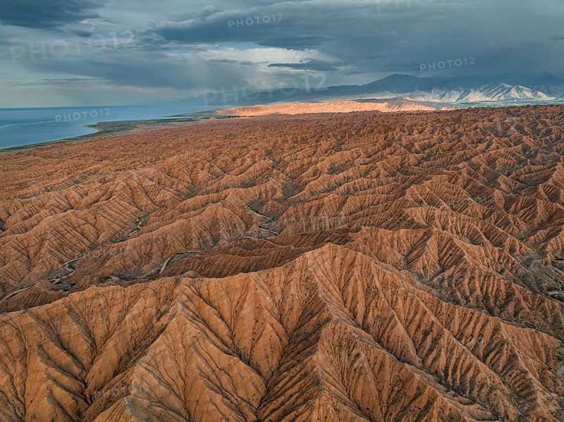 Landscape of eroded hills, badlands at sunset, Issyk Kul Lake in the background, aerial view, Canyon of the Forgotten Rivers, Issyk Kul, Kyrgyzstan, Asia
