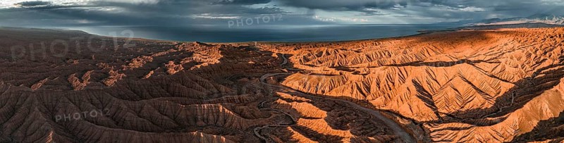 Panorama, landscape of eroded hills, badlands at sunset, Issyk Kul Lake in the background, aerial view, Canyon of the Forgotten Rivers, Issyk Kul, Kyrgyzstan, Asia