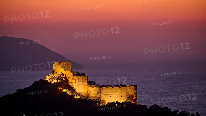 View of an illuminated castle ruin at dusk, surrounded by sea and mountains under a colourful sky, Kritinia Castle, St John's Castle, Kritinia, Rhodes, Dodecanese, Greek Islands, Greece, Europe