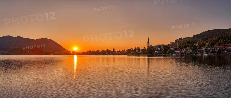 A warm, peaceful sunset picture with a lake, surrounding mountains and a village, Schliersee