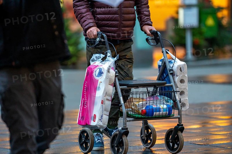 Man with rollator buys 2 large packs of toilet paper, The city centre of Bochum, on the day of the opening of the Christmas light decoration, usually also of the Christmas market, which remained closed due to the 2nd Corona crisis lockdown, empty shopping streets, Bochum, North Rhine-Westphalia, Germany, compulsory masks in the city centre, Europe