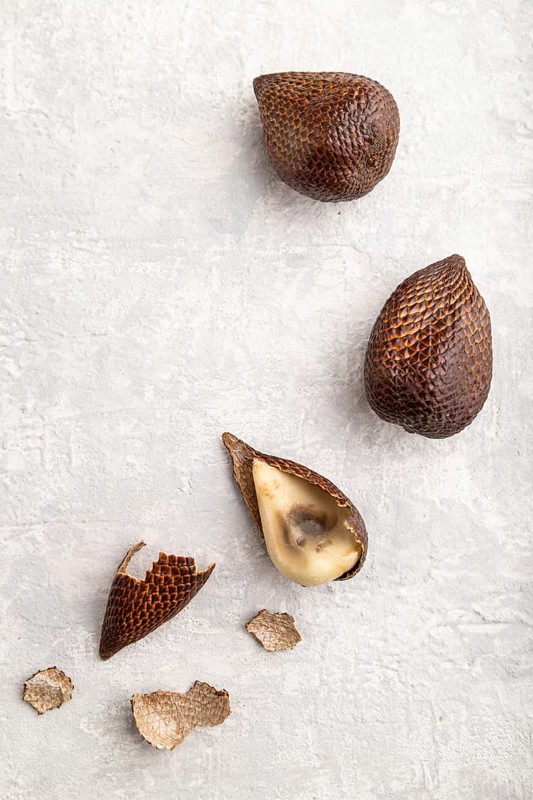 Salak or snake fruit on gray concrete background. Top view, flat lay, close up. Tropical, healthy food, summer, exotic, minimalism