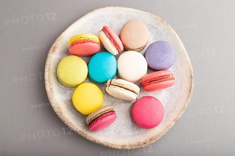 Multicolored macaroons on ceramic plate on gray pastel background. top view, close up, still life, flat lay. Breakfast, morning, concept