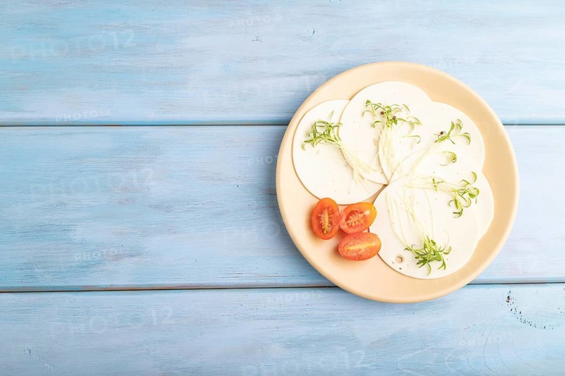 White cheese with tomatoes and cilantro microgreen on blue wooden background. top view, flat lay, copy space