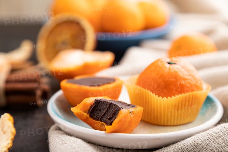Truffle chocolate tangerine candies on a black concrete background and linen textile. Side view, close up, selective focus