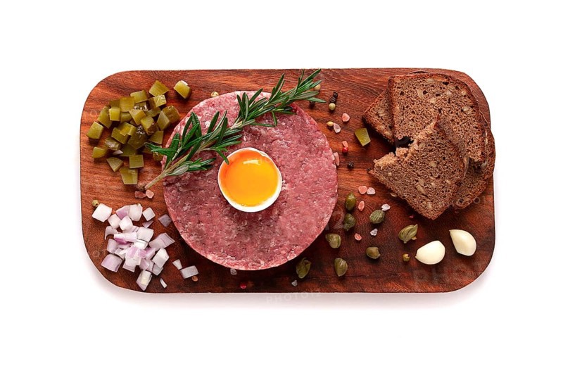 Beef tartare, with egg, capers, gherkins and bread, on a white background, top view, close up, horizontal, no people