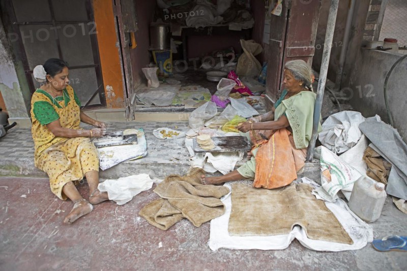 Indian woman making pappadam or Indian bread on the footpath, Kochi, Kerala, India, Asia