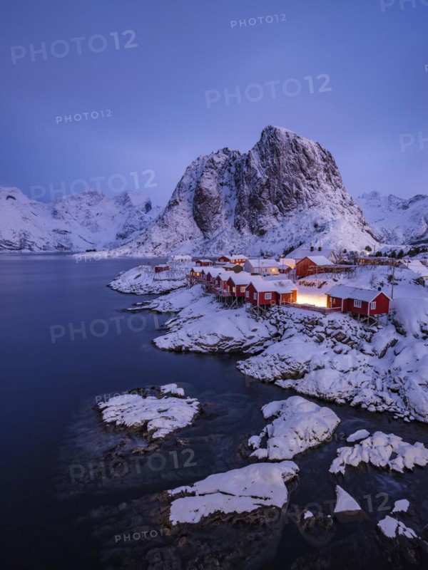 Rorbuer huts of Hamnoy at the fjord at dusk, snowy mountains in the background, Hamnøy, Reine, Moskenesøya, Lofoten, Norway, Europe