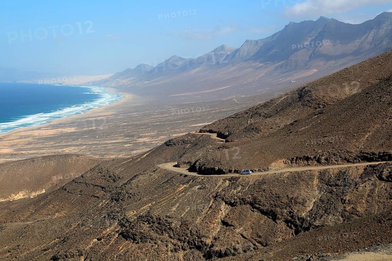 Car driving on unsurfaced road, Atlantic Ocean coast, Jandia peninsula, Fuerteventura, Canary Islands, Spain, Europe