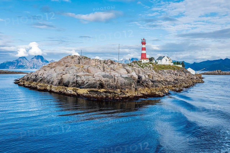 Lighthouse on island Skrova, rocky small island, view towards Lofoten islands, mountain Vågekallen near Henningsvær in the back, peak covered by clouds, Norway, Europe