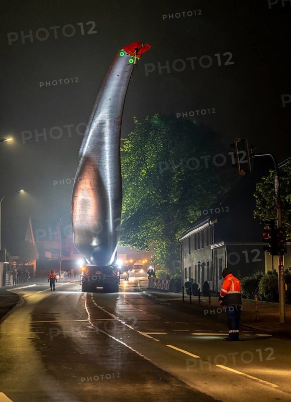 Transport of a 68 metre long, 22 tonne blade of a wind turbine, here in Breckerfeld, with a self-propelled Blade-Lifter vehicle, over a 40 km long route, over 2 nights, in the Bergisches Land, through towns, villages, over country roads, narrow through roads, to the construction site of the wind turbine near Hagen, North Rhine-Westphalia, Germany, Europe