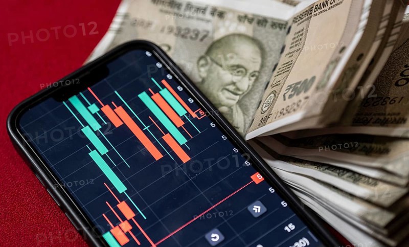 Stock market graph or chart display on a mobile phone against Indian 500 rupee paper currency note