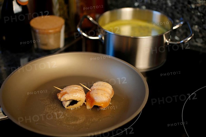 Southern German cuisine, preparation of sorrel soup with char, frying raw char fillets in a pan, oil, freshwater fish, savoury, salty, cooking pot with vegetable stock in the back, traditional cuisine, food photography, studio, Germany, Europe