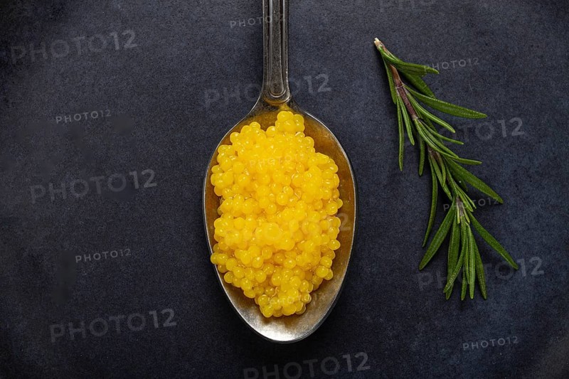 Pearl yuzu, yuzu caviar - pearl, on a spoon, top view, on a dark gray plate, there are no people.