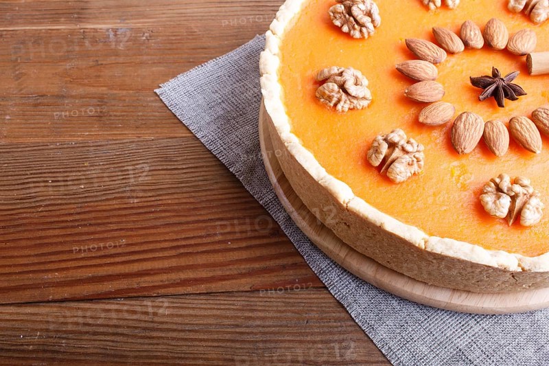 Traditional american sweet pumpkin pie decorated with nuts, on brown wooden background. close up, copy space