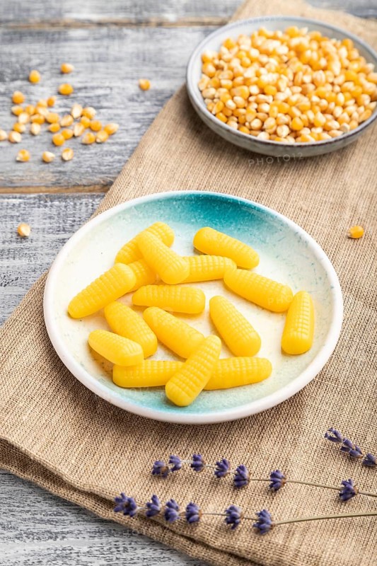 Jelly corn candies on gray wooden background and linen textile. close up, side view