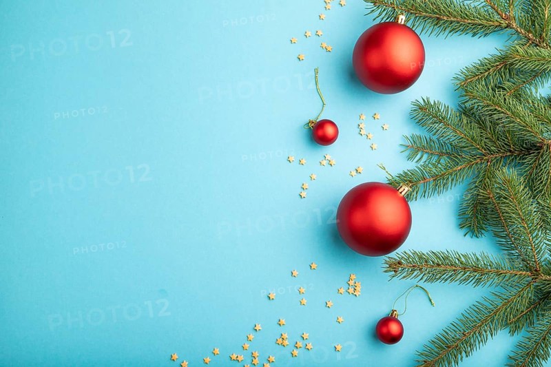 Christmas or New Year composition. Decorations, red balls, fir and spruce branches, on a blue paper background. Top view, copy space, flat lay