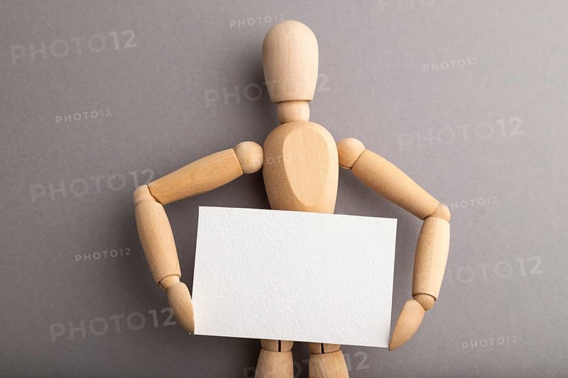 Wooden mannequin holding blank poster on gray pastel background. copy space, isolated, presentation concept