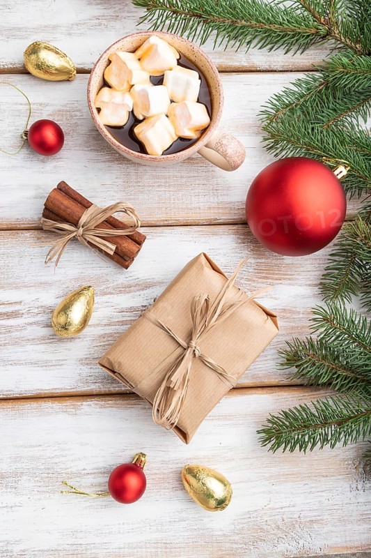 Christmas or New Year composition. Decorations, box, red balls, cinnamon, fir and spruce branches, cup of coffee, on a white wooden background. Top view, flat lay