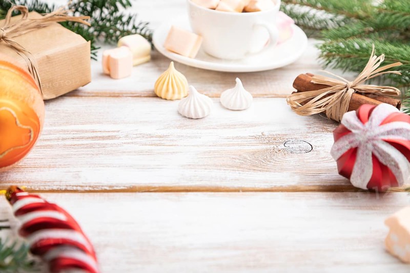 Christmas or New Year composition. Decorations, box, balls, cinnamon, fir and spruce branches, cup of coffee, on a white wooden background. Side view, copy space, selective focus