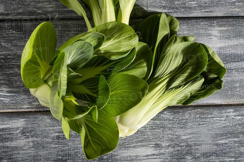 Fresh green bok choy or pac choi chinese cabbage on a gray wooden background. Hard light, contrast. Top view, close up, flat lay