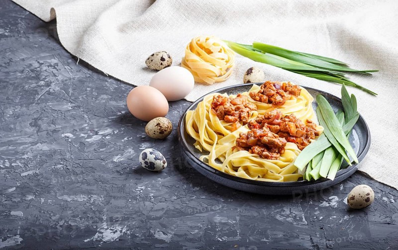 Tagliatelle bolognese pasta with minced meat on a black concrete background. side view, close up, copy space