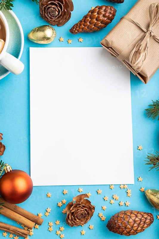 Christmas or New Year composition, template. Decorations, box, cinnamon, cones, fir and spruce branches, cup of coffee, on a blue paper background. Top view, copy space, flat lay