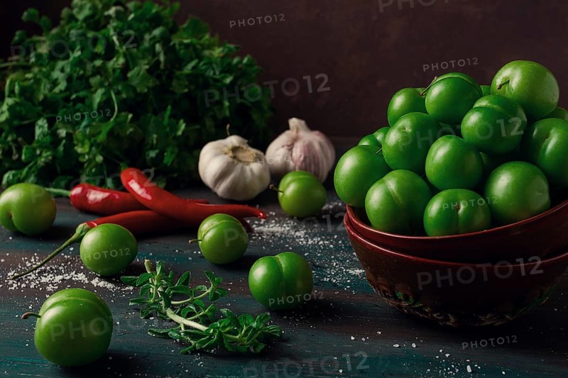Tkemali, green cherry plum, with ingredients for sauce, cilantro, mint, hot pepper, garlic, on a wooden table, close-up, rustic, food background, no people, selective focus
