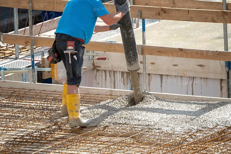 Construction site, concreting, the floor slab of a building is concreted, the concrete is pumped onto the reinforced concrete mats, spreading the concrete