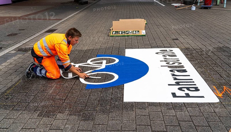 Application of road markings for a cycle lane, Rüttenscheider Straße in Essen, in the shopping and gastronomy district, cyclists have right of way over motorised vehicles, part of a cycle axis through Essen's city centre