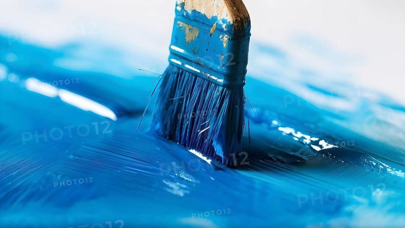 Thick paintbrush dipped in blue bristles dripping onto a white background, AI generated