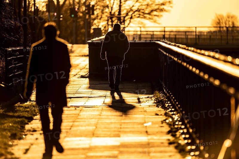 Man, elderly, walking on a pavement, a second man follows him, into the setting sun, long cast shadow, symbolic image, Essen, North Rhine-Westphalia, Germany, Europe