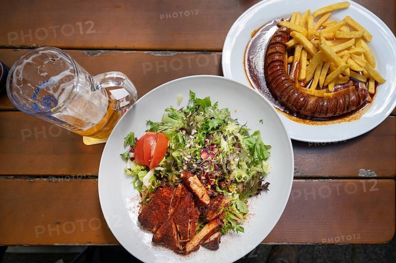 Salad with turkey strips and currywurst with French fries served in a garden withe, Bavaria, Germany, Europe