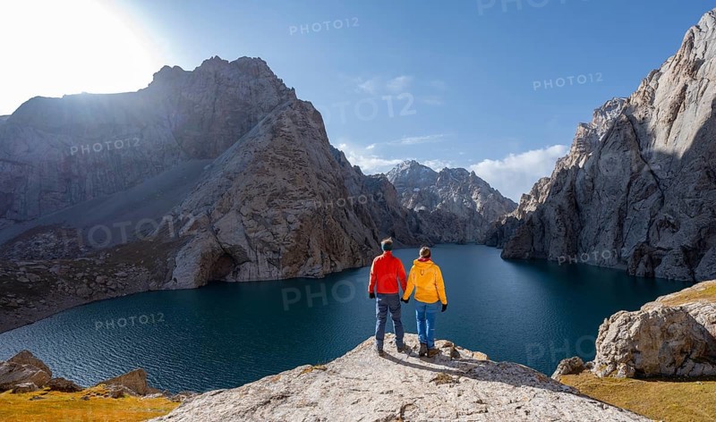 Couple at the blue mountain lake between rocky steep mountain peaks, Kol Suu Lake, Sary Beles Mountains, Naryn Province, Kyrgyzstan, Asia