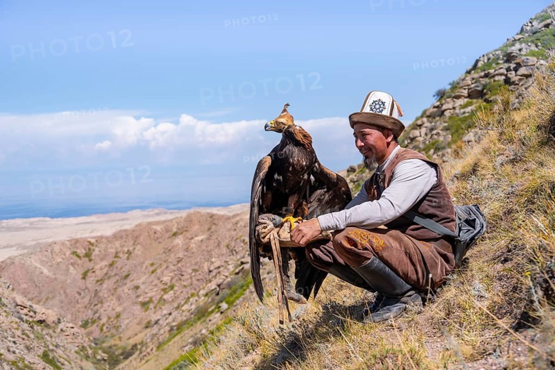 Traditional Kyrgyz eagle hunter with eagle in the mountains, near Kysyl-Suu, Kyrgyzstan, Asia