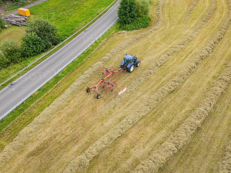 Aerial view of a tractor with hay machine in a field next to a country road, Dachtel. Black Forest, Germany, Europe