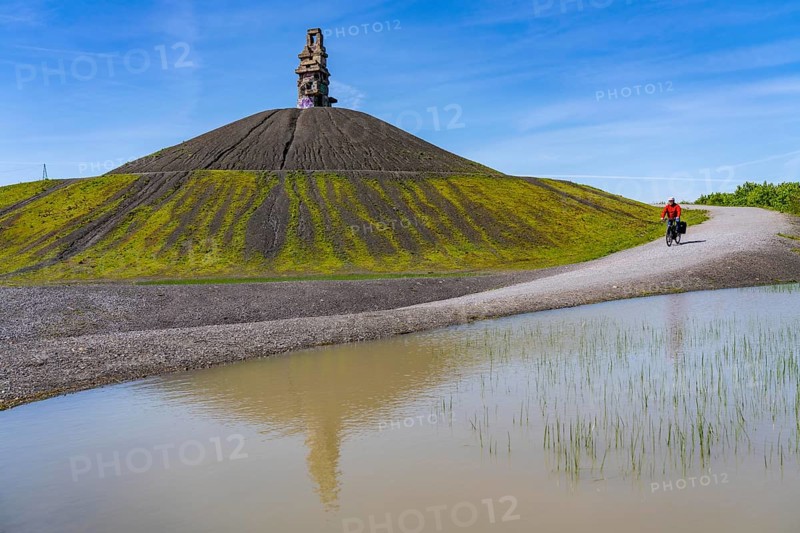 Cyclist on the Rheinelbe spoil tip in Gelsenkirchen, 100 metre high spoil tip, landscape park, with the sculpture Himmelsleiter, made of concrete parts of the former Rheinelbe colliery, Gelsenkirchen, North Rhine-Westphalia, Germany, Europe