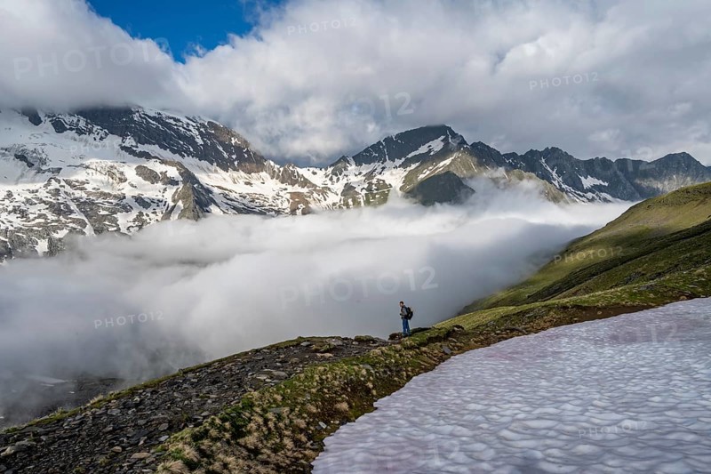 Mountaineer in front of mountain landscape with high fog in the valley, summit Hochfeiler and Hochsteller with clouds, glacier Schlegeiskees, Berliner Höhenweg, Zillertal Alps, Tyrol, Austria, Europe