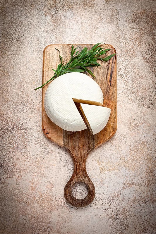 Head of Georgian cheese, Imereti variety, top view, on a cutting board