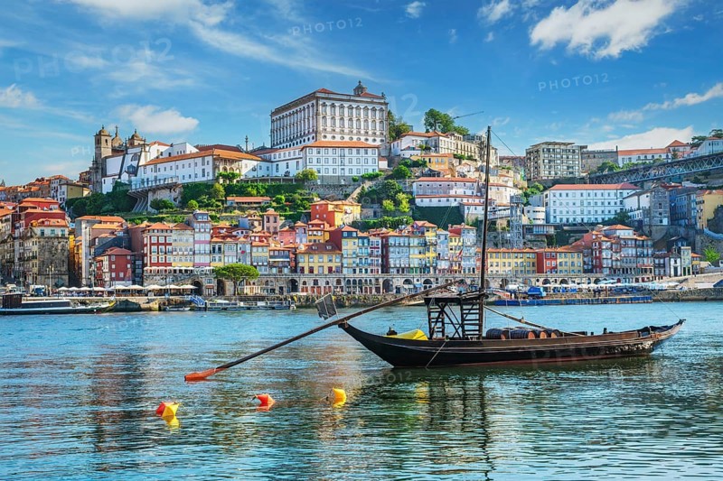 View of Porto city and Douro river with traditional boats with port wine barrels from famous tourist viewpoint Marginal de Gaia riverfront. Porto, Vila Nova de Gaia, Portugal, Europe