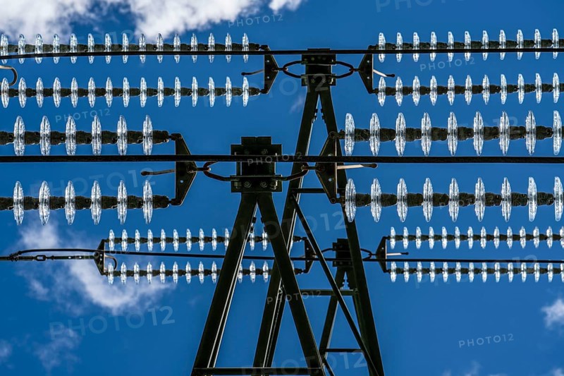 Insulators made of glass on a high-voltage line, they hang on the pylons as a suspension device between the pylon and the live, non-insulated cable, extra-high voltage line, symbolic image energy